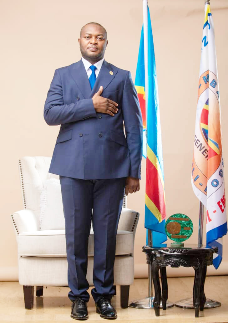 Le Président Gaston Mfumu devant le drapeau national et l'étendard du G4